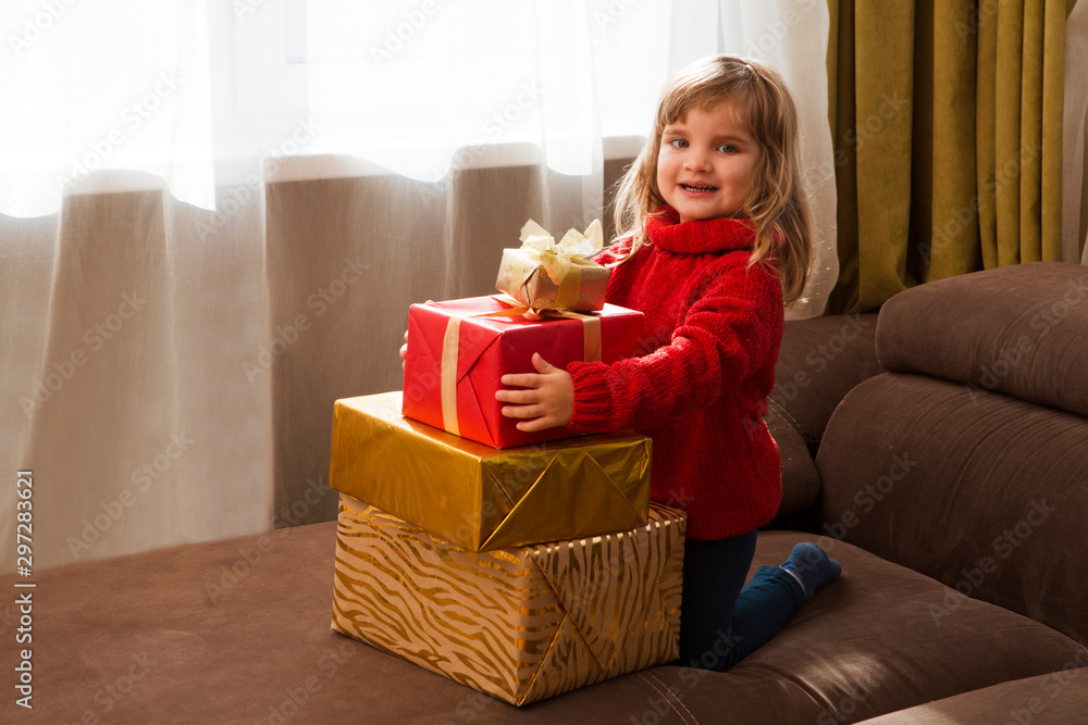 Cute child girl in a red sweater with Christmas gift boxes at home Cute child girl in a red sweater with Christmas gift boxes at home