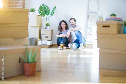 Middle age senior romantic couple in love sitting on the apartment floor with cardboard boxes around and smiling happy for moving to a new home © Krakenimages.com