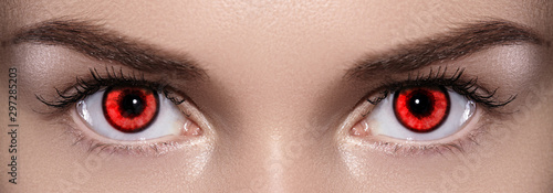 Close-up of Woman Eyes. Halloween Makeup. Devil, Vampire or Monster Eye Lens. Luminous Red Eyes