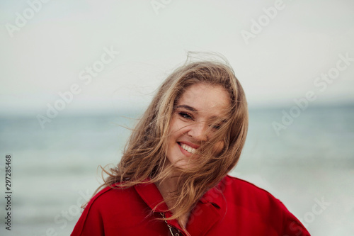 Beautiful happy woman in red coat walking on the beach