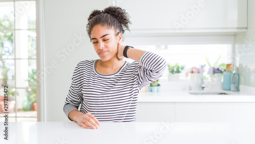Beautiful african american woman with afro hair wearing casual striped sweater Suffering of neck ache injury  touching neck with hand  muscular pain