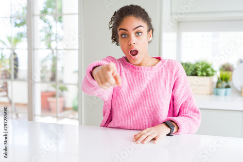 Beautiful african american woman with afro hair wearing casual pink sweater pointing displeased and frustrated to the camera  angry and furious with you