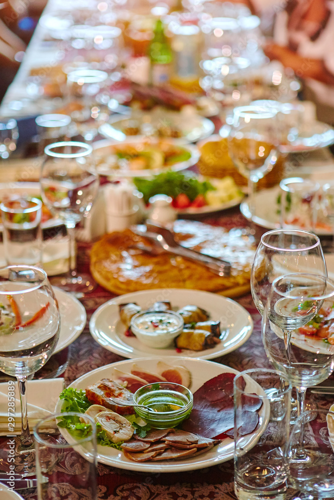 Fototapeta premium A group of people at a long table with food. The concept for the joint celebration of memorable dates or holidays