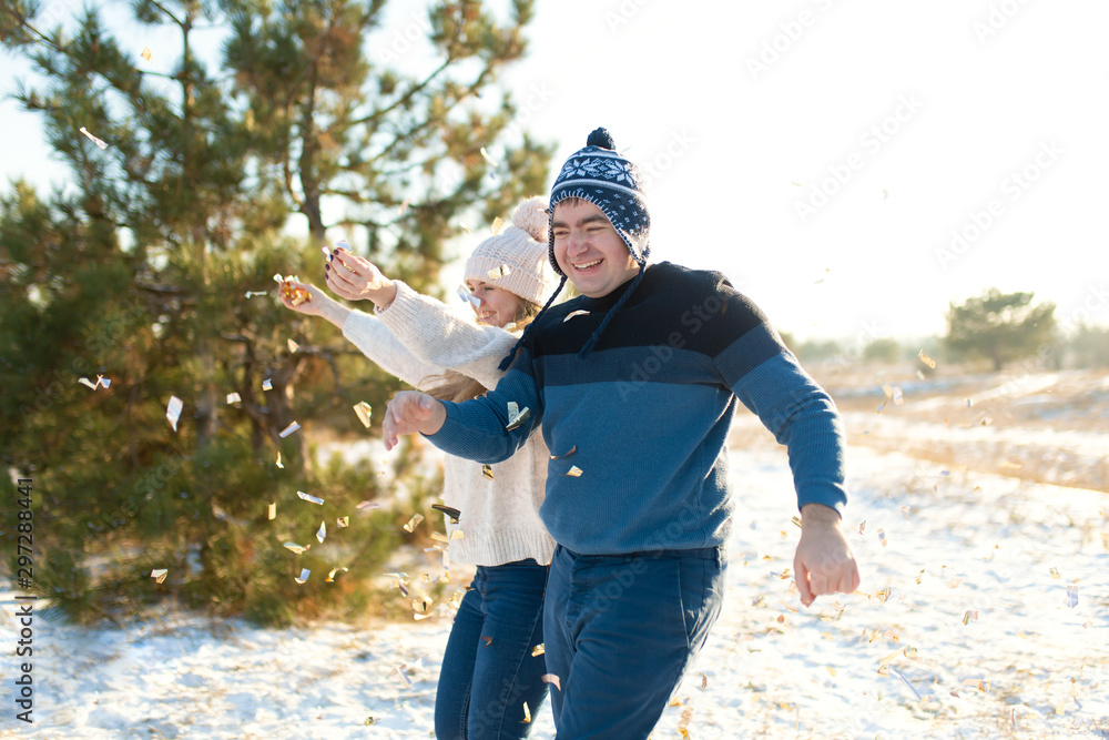 The guy with the girl throw confetti in the winter forest The guy with the girl throw confetti in the winter forest