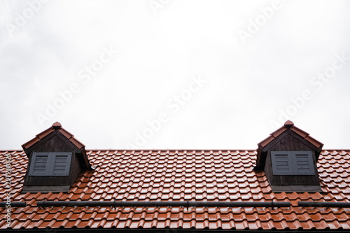 Roof with terracotta tiles on a background of cloudy gray autumn rainy sky. autumn mood. Cold tone. Rainy day. Horizontal orientation.