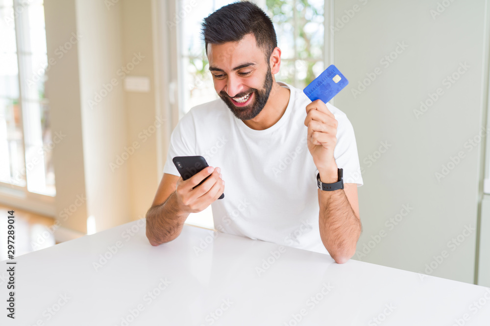 Handsome man using credit card to pay online with smartphone Handsome man using credit card to pay online with smartphone