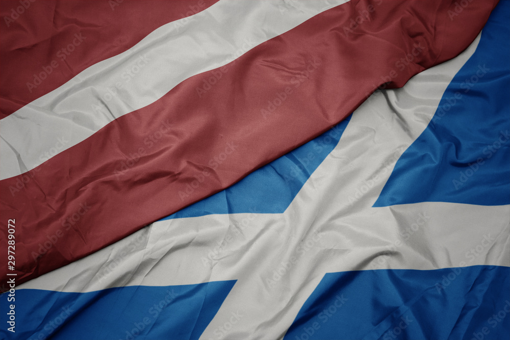 waving colorful flag of scotland and national flag of latvia. waving colorful flag of scotland and national flag of latvia.