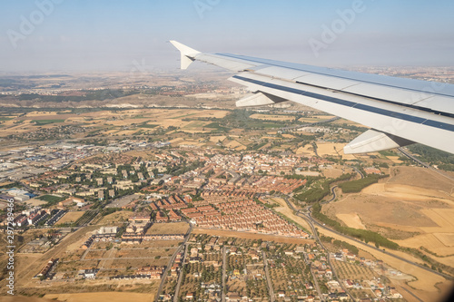 Looking through aircraft window during flight. Aircraft wing over blue skies and cityscape .Copy space.