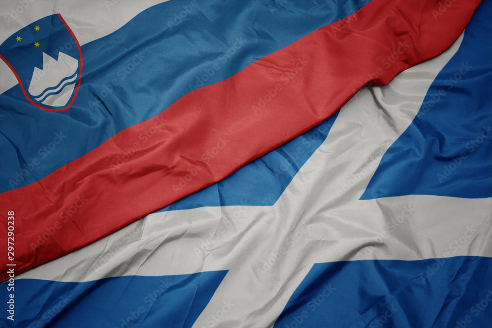 waving colorful flag of scotland and national flag of slovenia.
