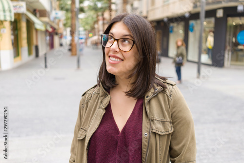 Beautiful young woman wearing glasses smiling confident at the streets of the town