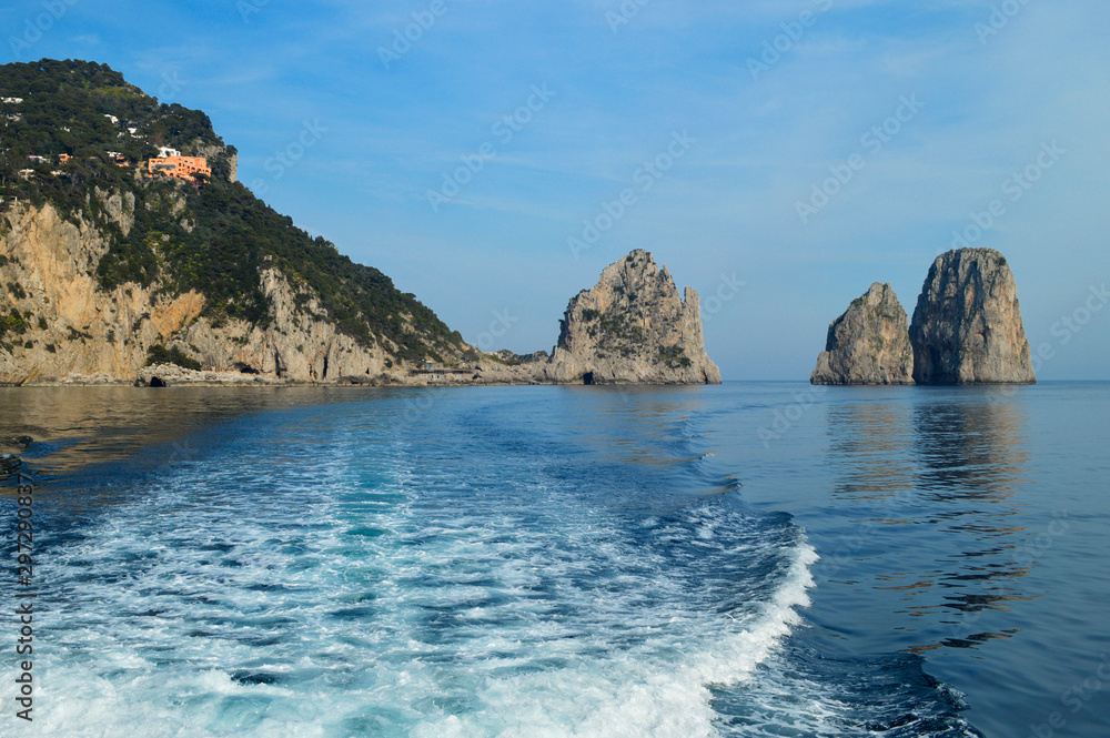 Beautiful view of the cliffs of Faraglioni, the sea and the island of Capri from the side of the boat.