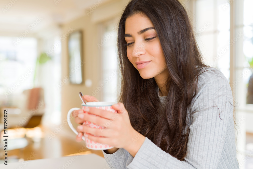 Beautiful young girl drinking a cup of coffee at home and smiling Beautiful young girl drinking a cup of coffee at home and smiling
