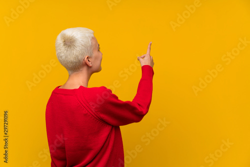 Photography Teenager girl with white short hair over yellow wall pointing back with the inde
