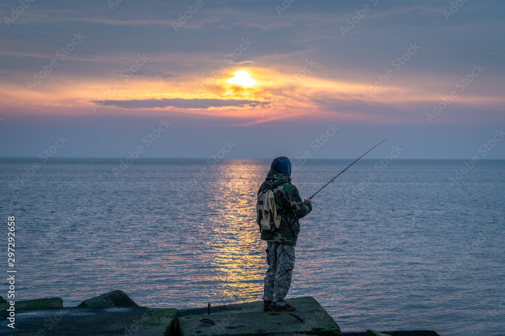 Man fishing from the pier during beautiful sunset 