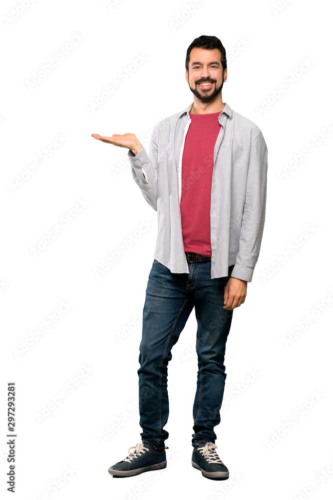 Full-length shot of Handsome man with beard holding copyspace imaginary on the palm to insert an ad over isolated white background Full-length shot of Handsome man with beard holding copyspace imaginary on the palm to insert an ad over isolated white background