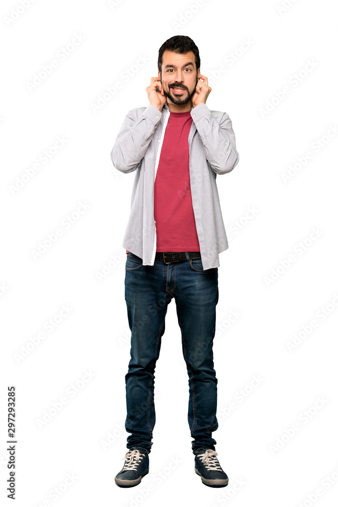 Full-length shot of Handsome man with beard frustrated and covering ears over isolated white background Full-length shot of Handsome man with beard frustrated and covering ears over isolated white background