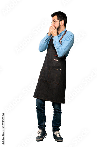 Full-length shot of Man with apron covering mouth and looking to the side over isolated white background © luismolinero