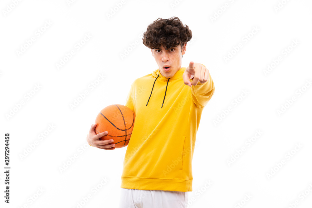Fototapeta premium Young basketball player man over isolated white wall surprised and pointing front