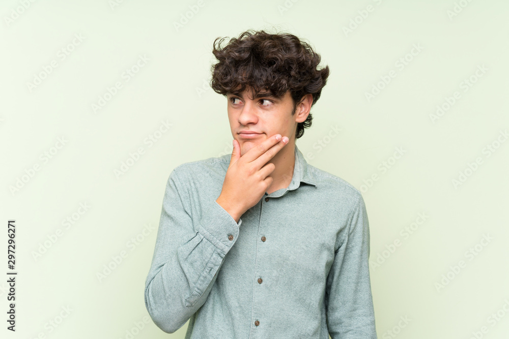 Young man over isolated green wall thinking an idea Young man over isolated green wall thinking an idea