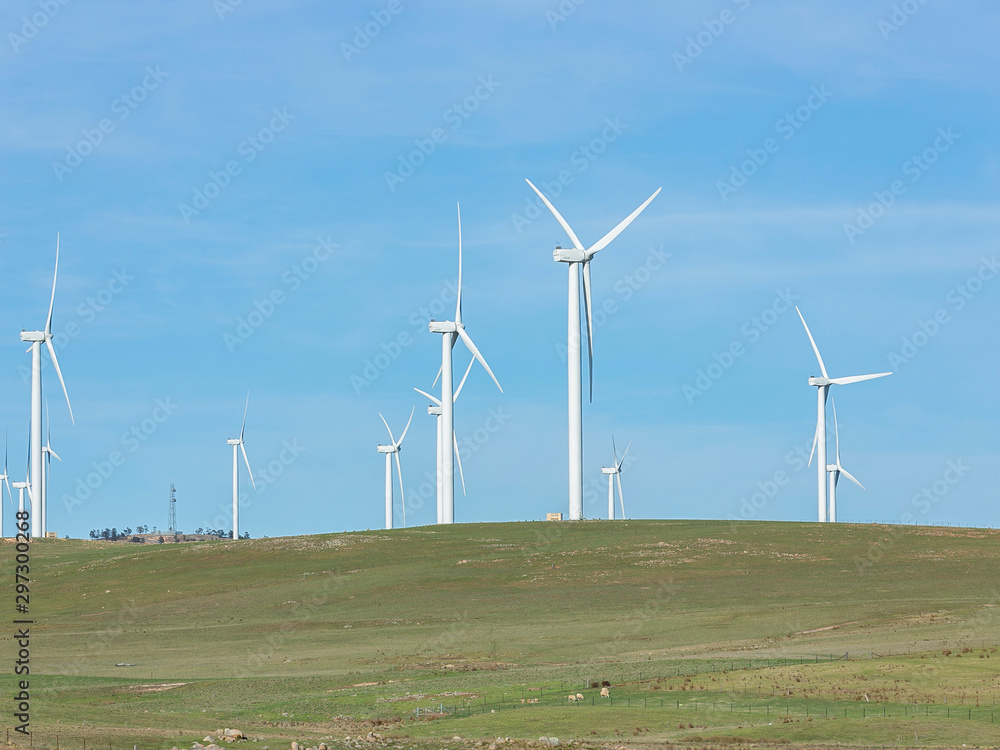 An array of large wind turbines moving to create kinetic energy for renewable energy supply on a sunny day located southeast of Lake George and north of Bungendore in New South Wales, Australia An array of large wind turbines moving to create kinetic energy for renewable energy supply on a sunny day located southeast of Lake George and north of Bungendore in New South Wales, Australia