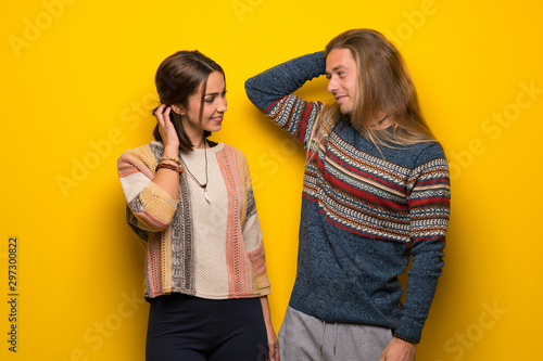 Hippie couple over yellow background thinking an idea while scratching head