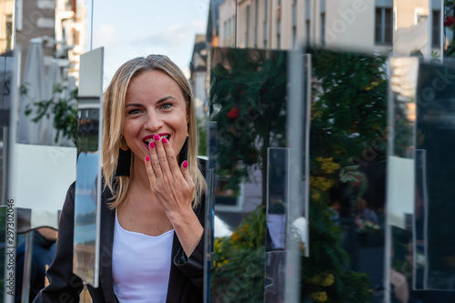 Portrait of a young, emotional, blonde woman through the installation of mirror - image