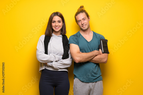 Group of athletes over yellow background keeping the arms crossed in frontal position
