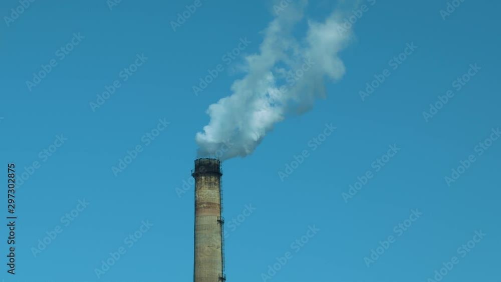 Smoking factory chimney against blue sky