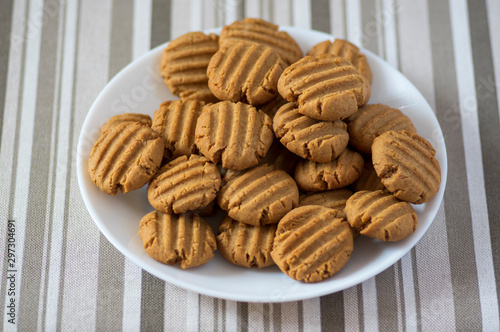 Pile of peanut butter biscuits on white plate, very tasty golden baked sweets, cookies served to eat