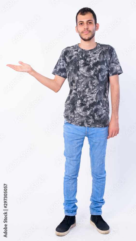 Full body shot of young bearded Persian man showing something Full body shot of young bearded Persian man showing something