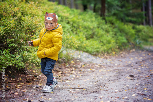 Fototapeta Naklejka Na Ścianę i Meble -  Cute blonde toddler boy with painted face, walking in the forest on a sunny day