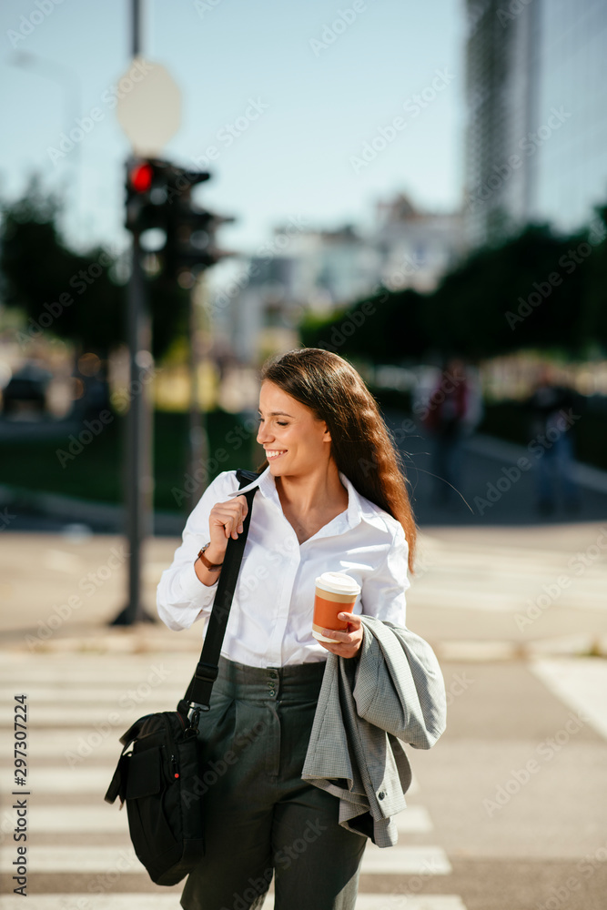 Fototapeta premium Portrait of young woman walking on the street with coffee