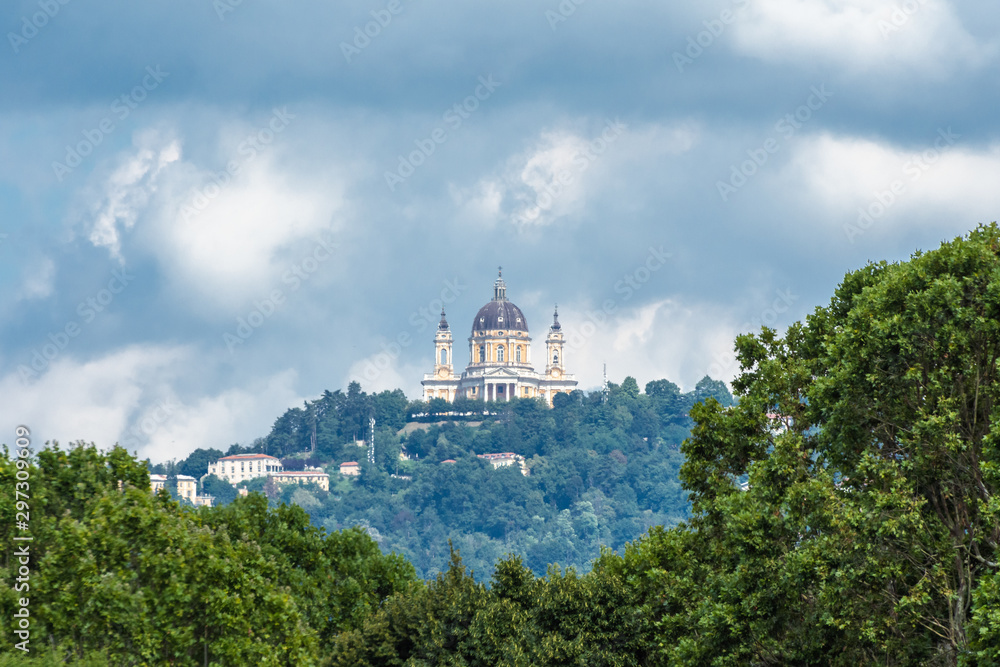 Superga church, a famous monument of Turin, with clouds on background and trees in first plane, Piedmont, Italy.