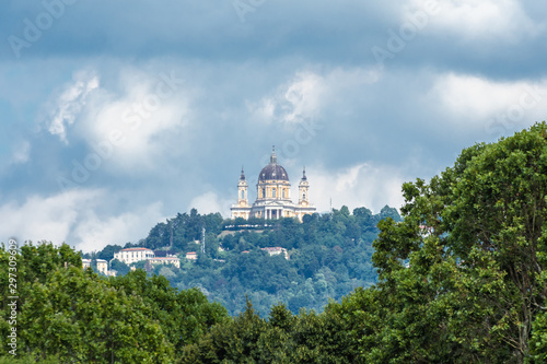 Superga church  a famous monument of Turin  with clouds on background and trees in first plane  Piedmont  Italy.