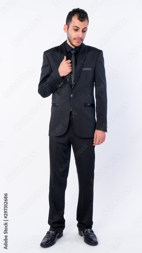 Full body shot of young bearded Persian businessman in suit looking down Full body shot of young bearded Persian businessman in suit looking down