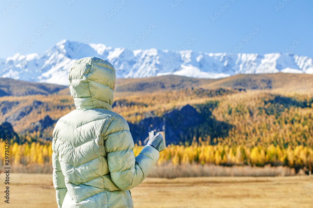 Woman drink tea on nature in autumn. A young tourist woman drinks a hot drink from a cup and enjoys the scenery in the mountains. Trekking travel concept. Woman drink tea on nature in autumn. A young tourist woman drinks a hot drink from a cup and enjoys the scenery in the mountains. Trekking travel concept.