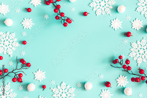 Christmas or winter composition. Snowflakes and red berries on mint background. Christmas, winter, new year concept. Flat lay, top view, copy space
