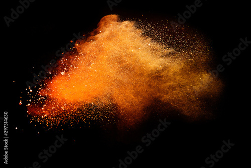 Abstract orange powder explosion isolated on black background.