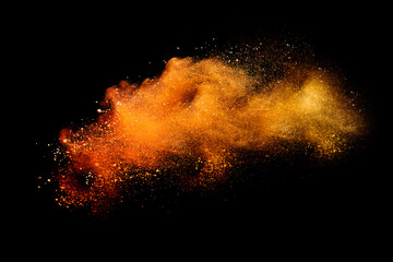 Abstract orange powder explosion isolated on black background.