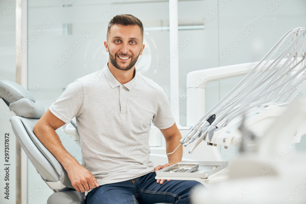 Fototapeta premium Front view of handsome male patient sitting on dental chair