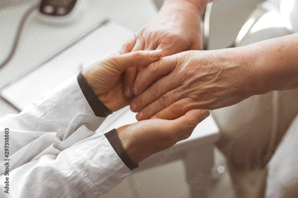 Fototapeta premium Doctor holds the elderly patient woman's hands while supporting her.