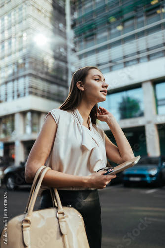 girl on the background of the business center holds the phone and looks with an expectant look into the distance, looking for someone