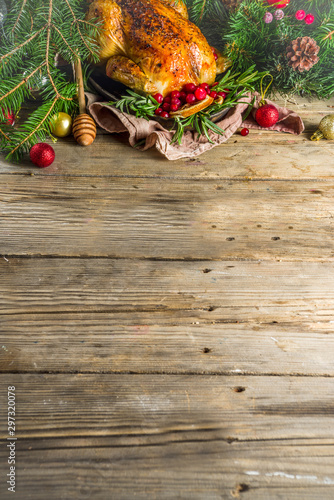 Traditional Christmas and Thanksgiving roasted whole chicken with fruit and rosemary. Rustic wooden table copy space with Christmas decoration