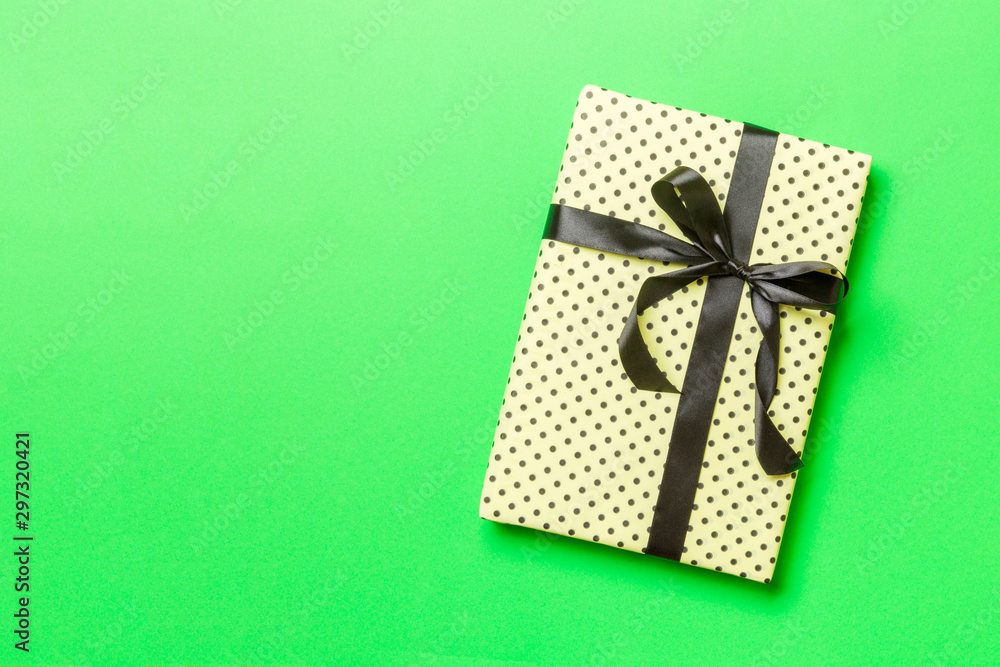 Top view Christmas present box with black bow on green background with copy space Top view Christmas present box with black bow on green background with copy space