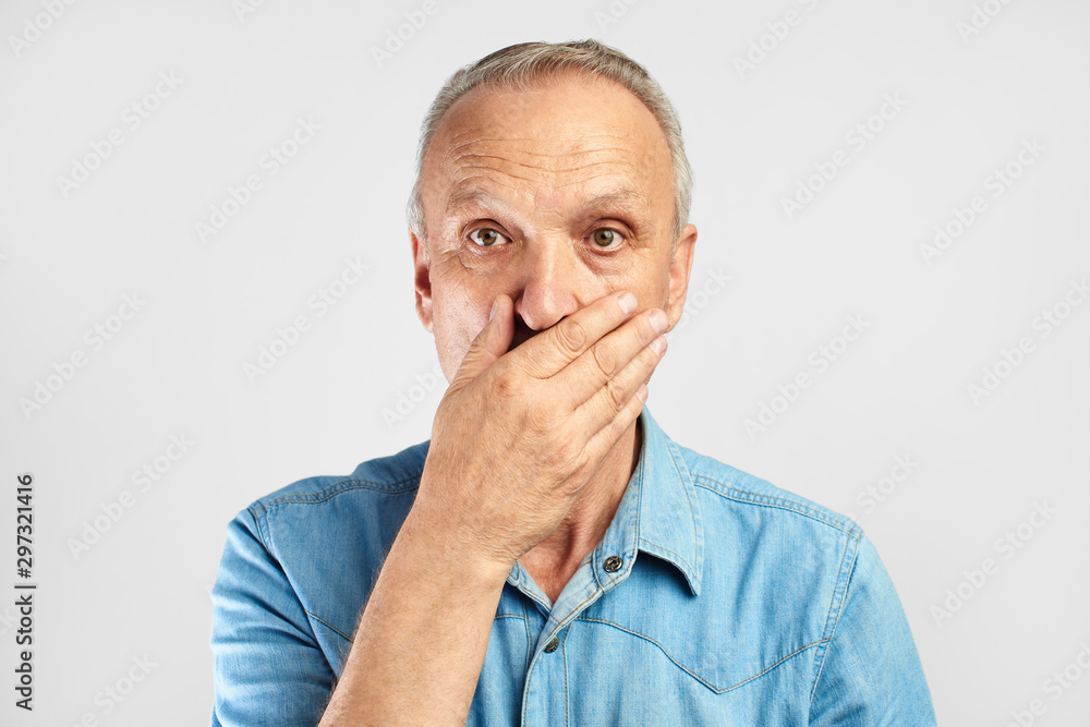 © amixstudio - Shocked surprised elderly gray-haired man fearfully closes mouth with hand isolated on white background, human emotions concept © amixstudio - Shocked surprised elderly gray-haired man fearfully closes mouth with hand isolated on white background, human emotions concept
