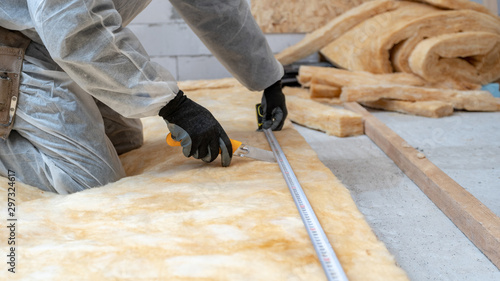 Professional workman installing thermal insulation rock wool under the roof photo