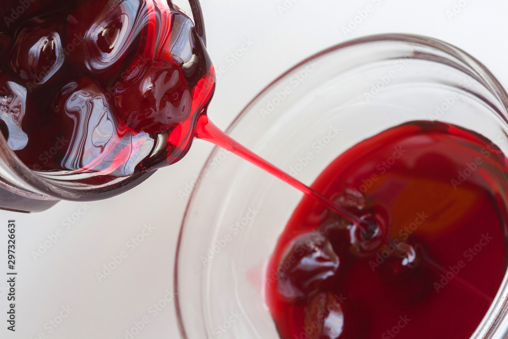 red cherry jam is poured from can into glass red cherry jam is poured from can into glass