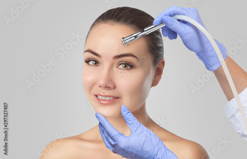 There is a woman, who is making the procedure Microdermabrasion of the facial skin in a beauty salon.Cosmetology and professional skin care.