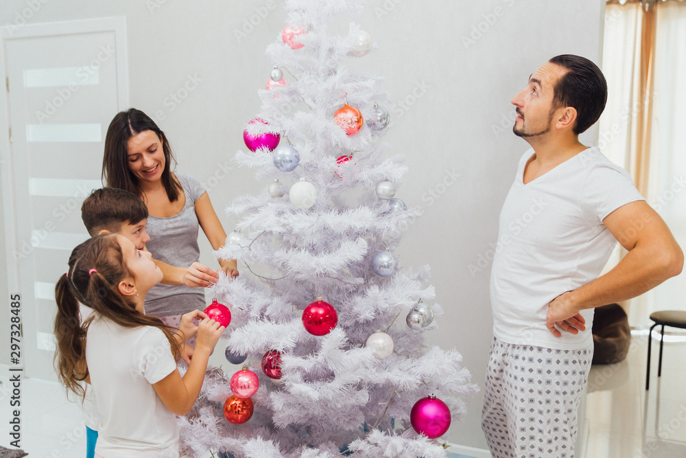 Parents with daughter and son dress up Christmas tree at home Parents with daughter and son dress up Christmas tree at home