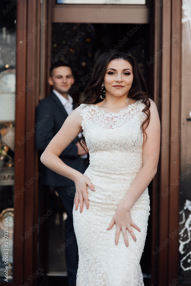 Fototapeta premium Trendy couple coming out of modern cafe. Love story. Lifestyle concept. Feelings of love between two people. Fashion photo. Guy in suit and Beautiful woman with professional make up and hairstyle.